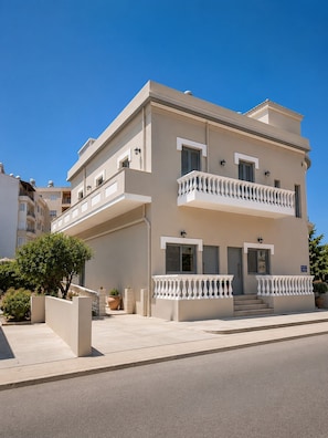A multi-story building with a balcony, a door, and a small garden area.