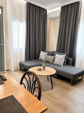 A modern living room with a sofa, a round coffee table, and a dining area with a table and chairs.