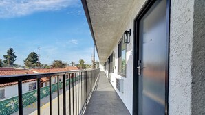 A balcony with a metal railing, a door, and windows. - Casablanca Inn (Bell Gardens)