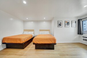 A hotel room with two beds, white walls, and a wooden floor.