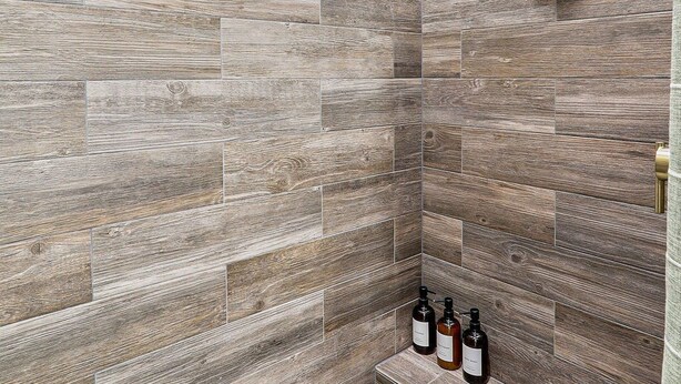 A shower area with a herringbone tile pattern and a handheld showerhead. - Book a Winter Stay! Hot Tub & Brand New Modern Cozy Home (Las Cruces)