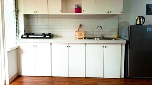 A compact kitchen with white cabinets, a stainless steel sink, and a black refrigerator. - Transient House Baguio Near Minesview With Backyard (Itogon)