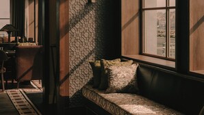 A cozy seating area with a patterned bench, a patterned wall, and a window with a view. - Maison Heler Metz, Curio Collection By Hilton (Metz)