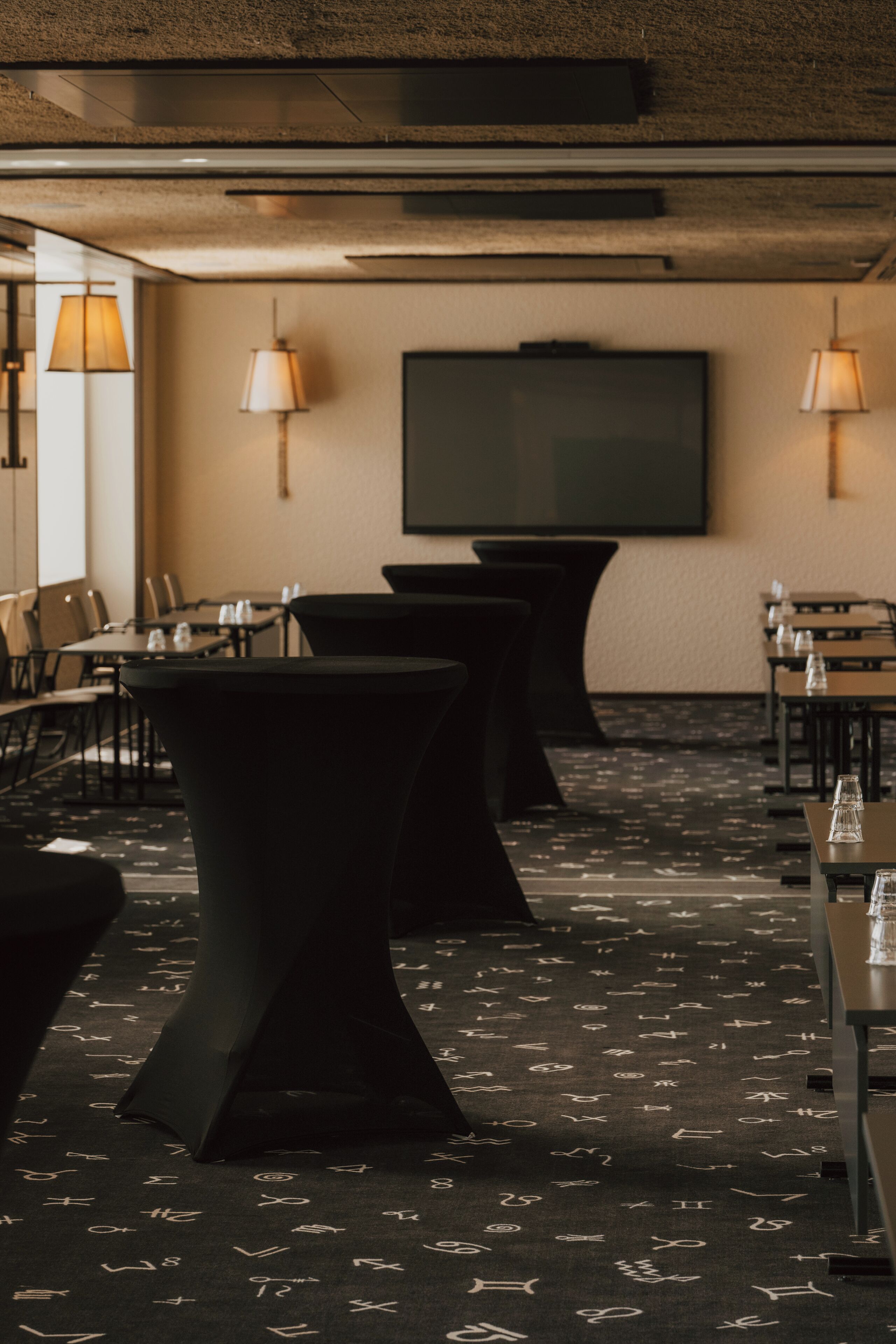 A conference room with tables, chairs, and a large screen.