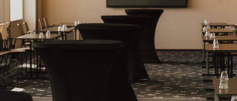 A conference room with tables, chairs, and a large screen.