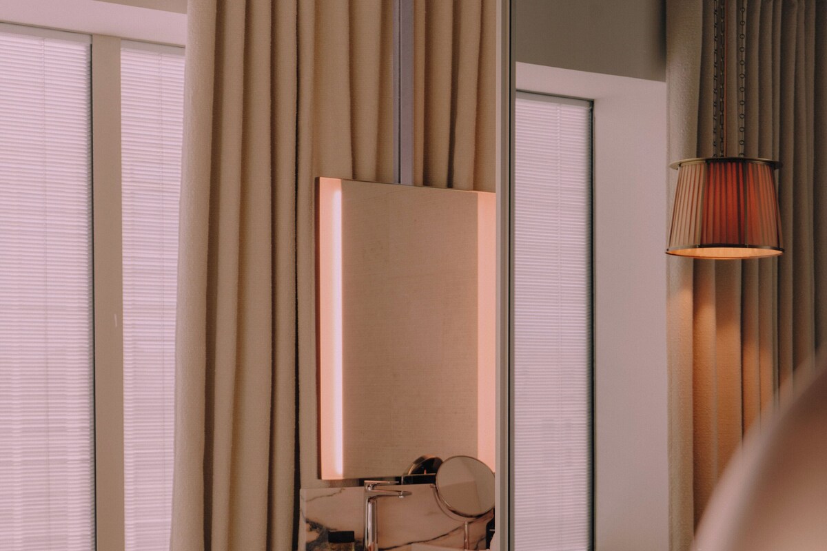 A hotel room with a bed, a vanity with a mirror, a sink, and a chair.