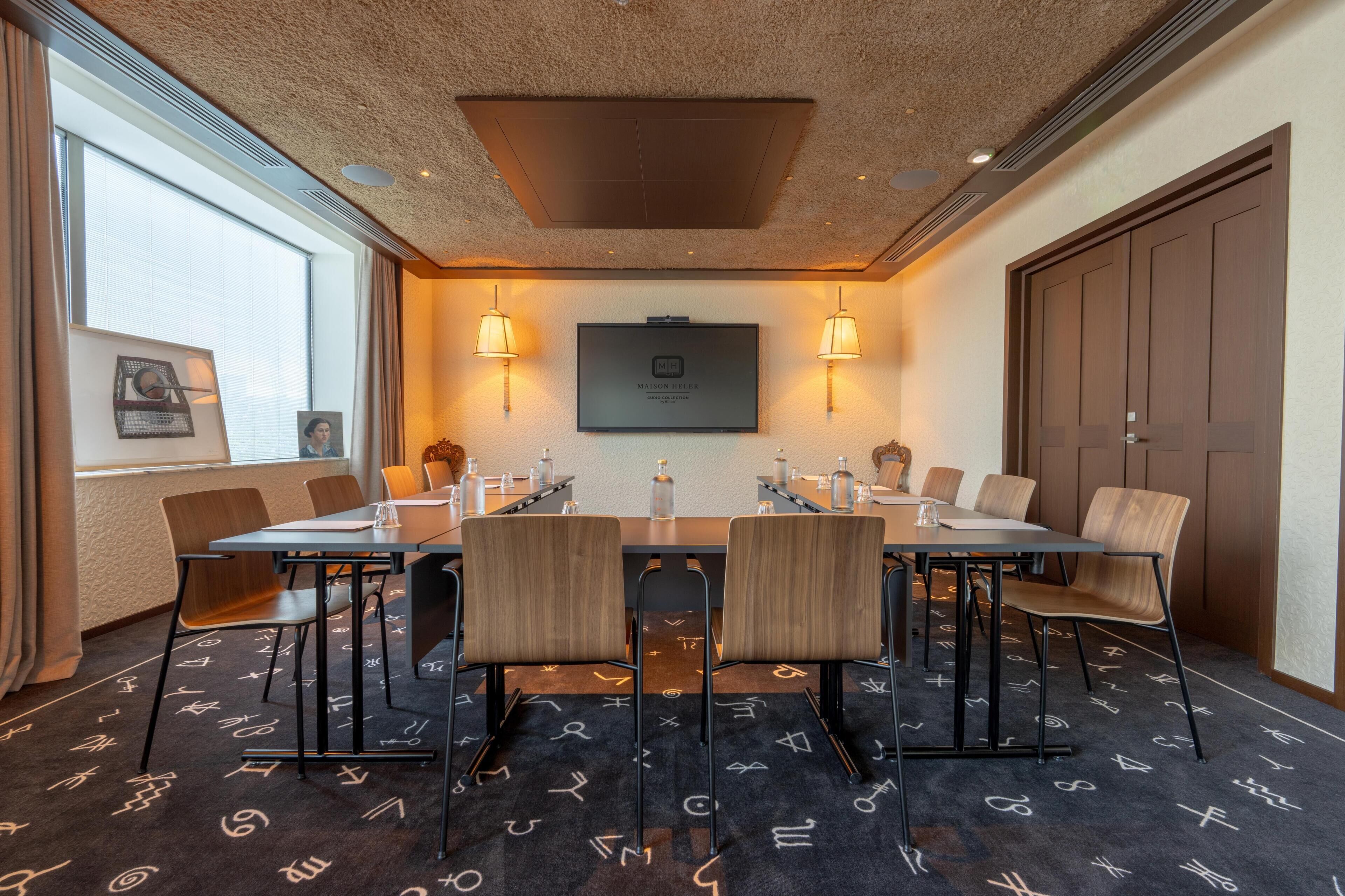 A conference room with a large table, chairs, and a mounted television.