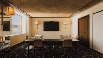 A conference room with a large table, chairs, and two wall-mounted lamps.