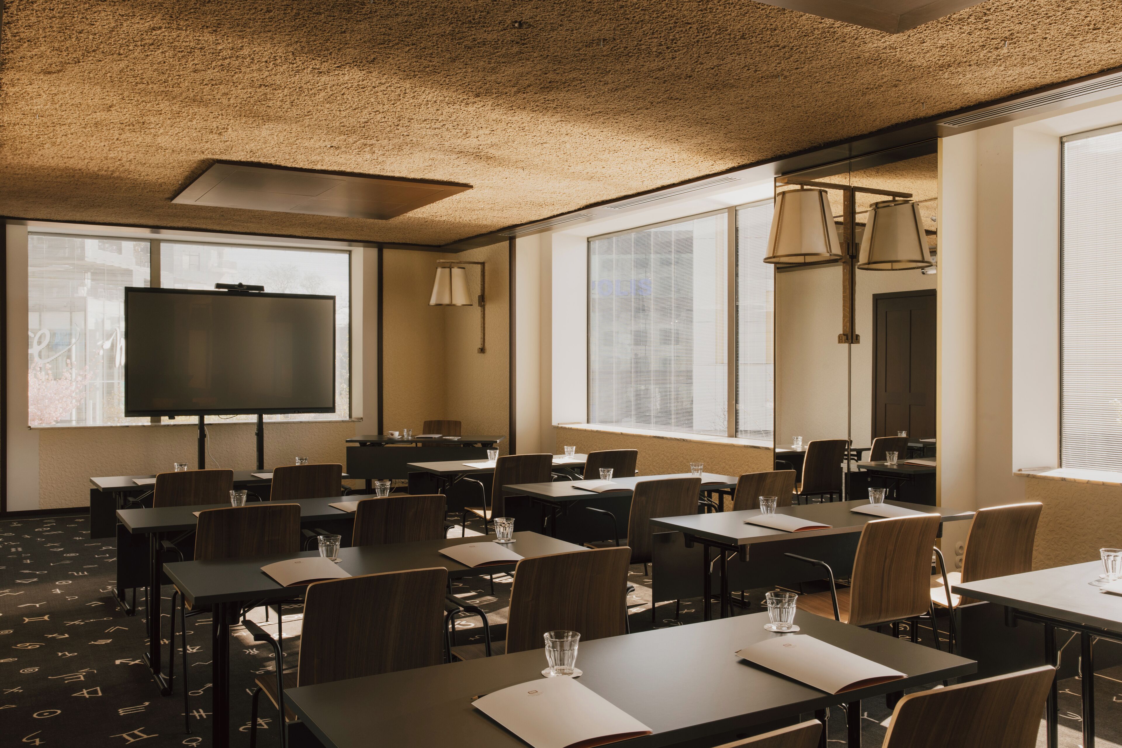 A conference room with tables, chairs, a projector screen, and large windows.