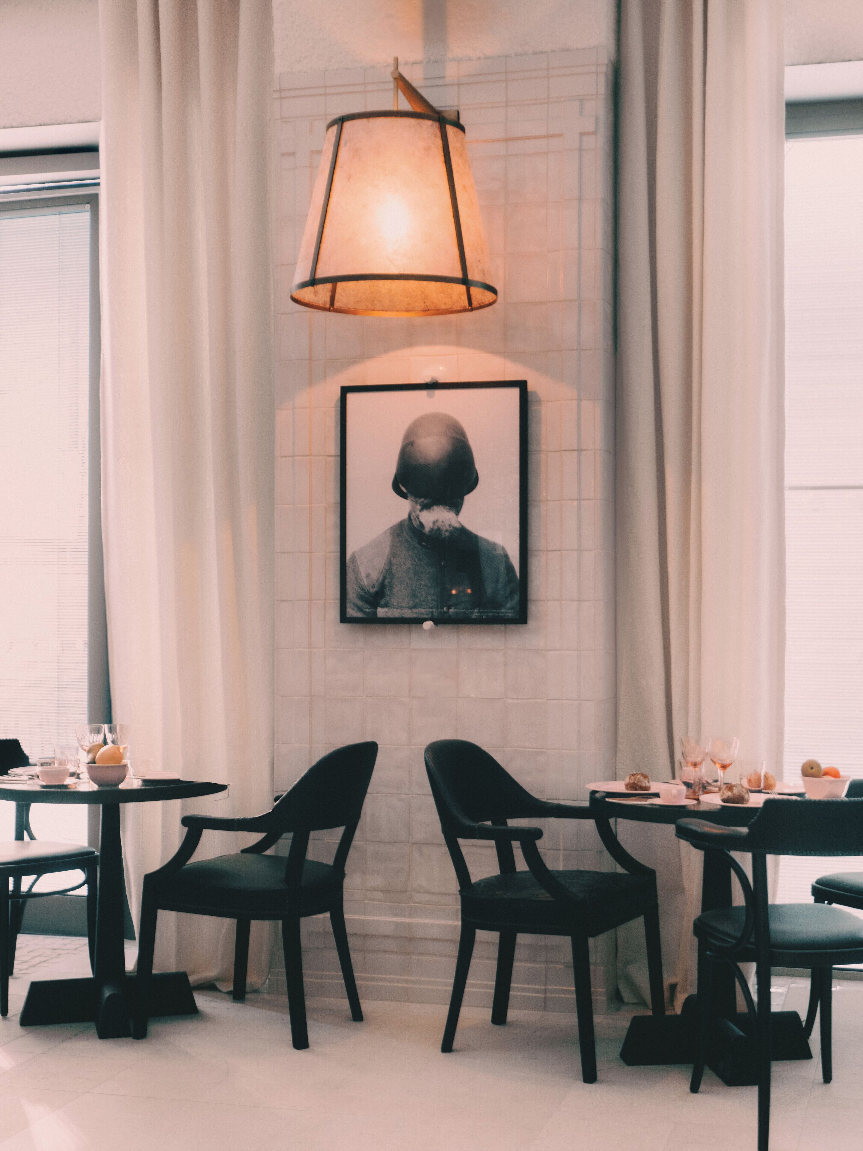 Un comedor con una mesa preparada para dos personas, con sillas negras y un cuadro en la pared.
