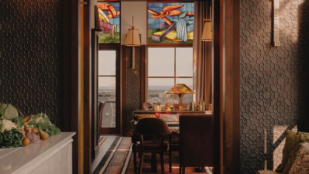 A hallway with a wooden bench, a table with a lamp, and a view through a stained glass window. - Maison Heler Metz, Curio Collection By Hilton (Metz)