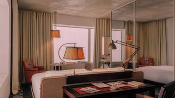 Una habitación de hotel con una cama, un escritorio con lámpara, una silla y un espejo grande.