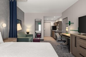 Une chambre d’hôtel équipée d’un lit, d’un bureau, d’une chaise, d’une télévision et d’un miroir.
