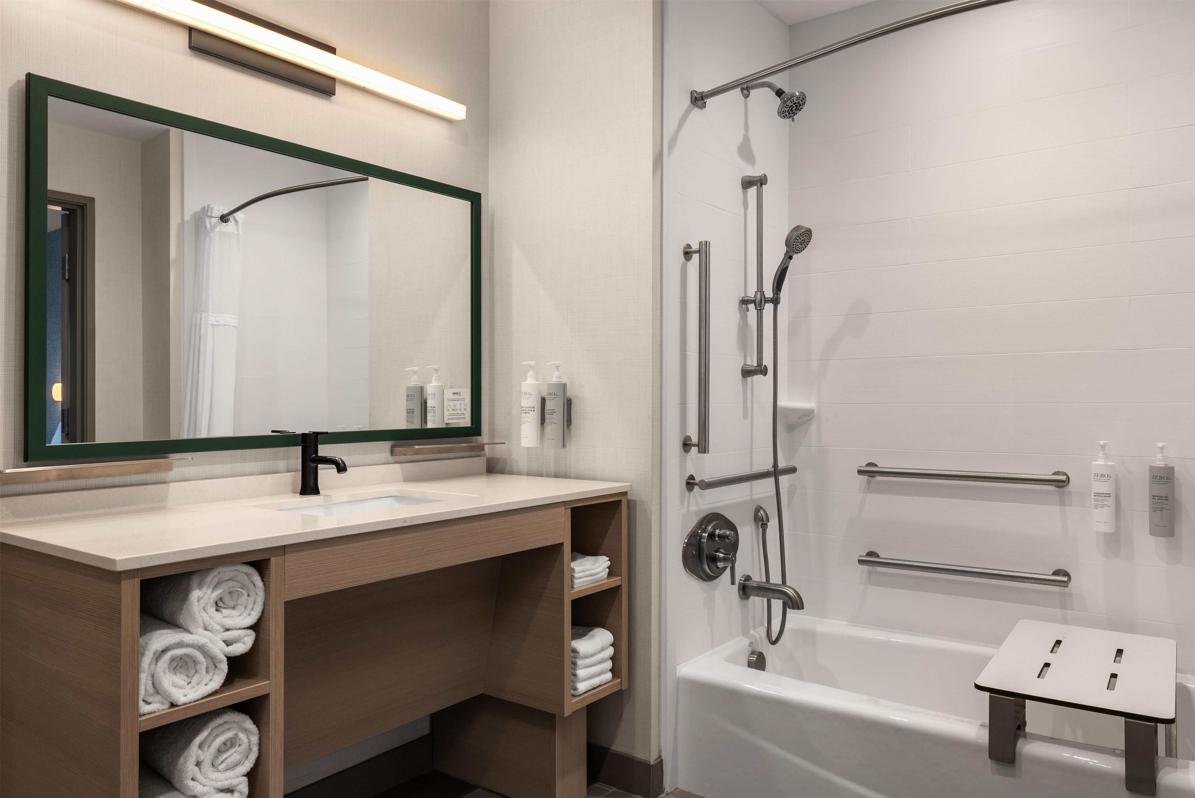 Un baño moderno con bañera, zona de ducha y tocador con espejo y perchero.
