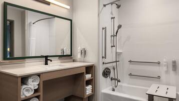Un baño moderno con bañera, zona de ducha y tocador con espejo y perchero.