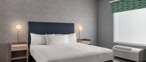 Une chambre d’hôtel avec un lit, des tables de chevet, un radiateur fixé au mur et une fenêtre donnant sur un paysage agréable.
