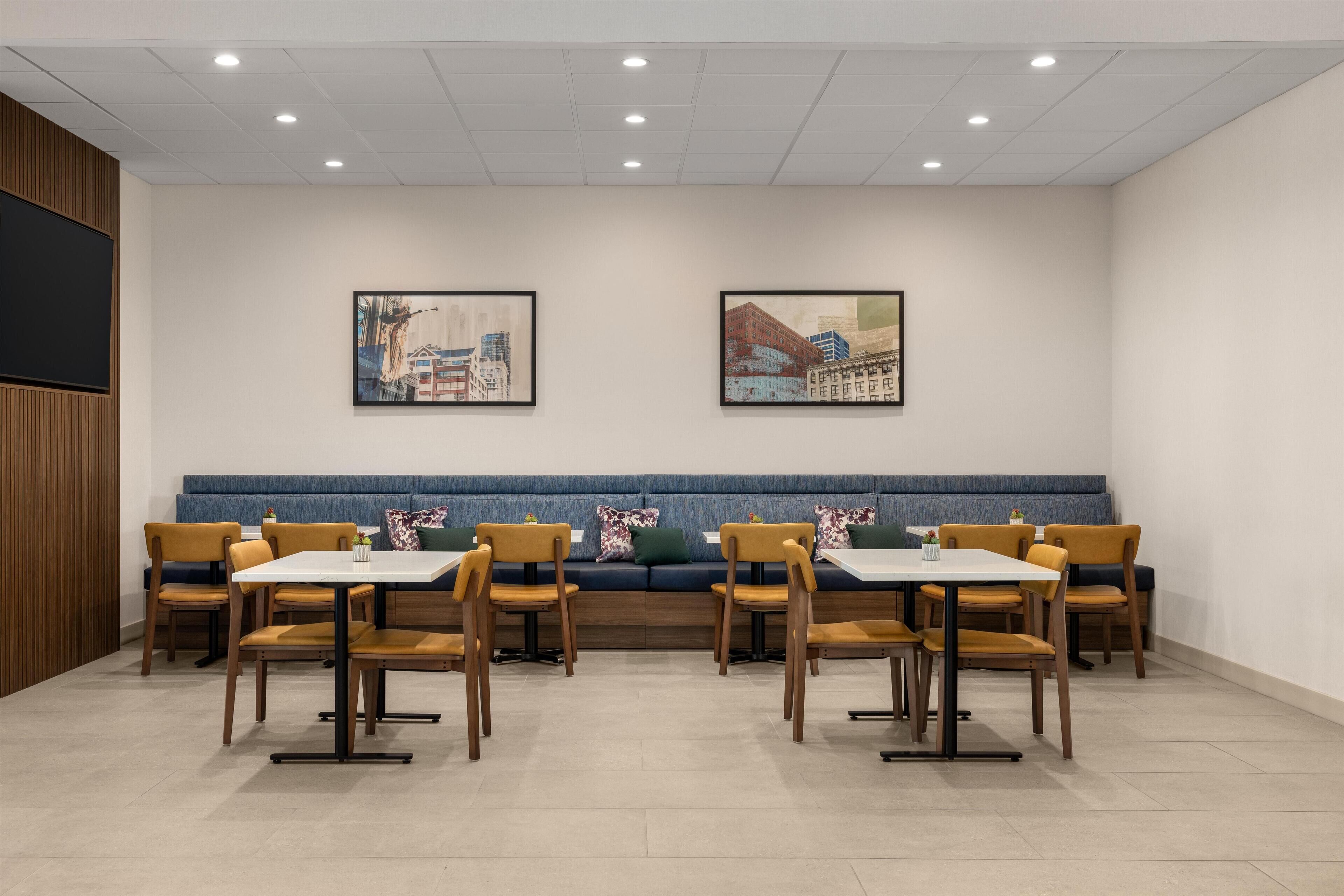 A dining area with a blue bench, wooden chairs, and a white table.