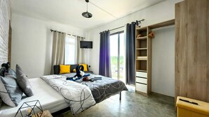 A modern bedroom with a bed, a wooden wardrobe, a desk, and a large window. - Charming and cosy Villa in Bel Ombre (Bel Ombre.)