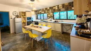 A modern kitchen with a central island, yellow chairs, and a stone backsplash. - Charming and cosy Villa in Bel Ombre (Bel Ombre.)