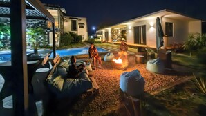 A modern outdoor pool area with a fire pit, seating, and a well-lit patio. - Charming and cosy Villa in Bel Ombre (Bel Ombre.)