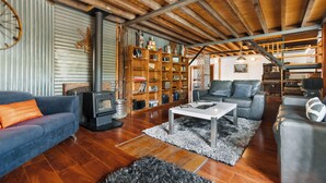 A cozy living room with a fireplace, a sofa, a coffee table, and a bookshelf. - The Workshops - Clyde Holiday Home (Clyde)
