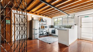 A modern kitchen with wooden beams, white cabinetry, and a built-in oven. - The Workshops - Clyde Holiday Home (Clyde)