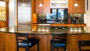 A modern kitchen with wooden cabinets, a large island with bar stools, and pendant lighting.