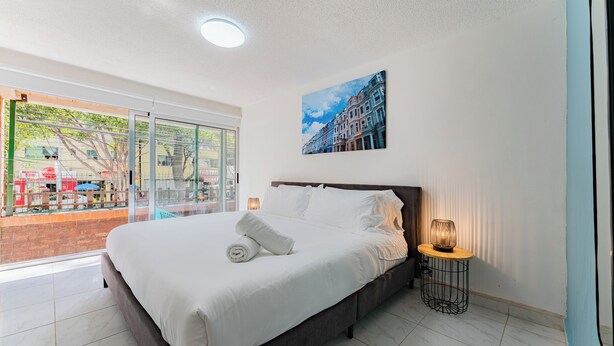 Een moderne hotelkamer met een groot bed, uitzicht op de stad en een schilderij aan de muur.