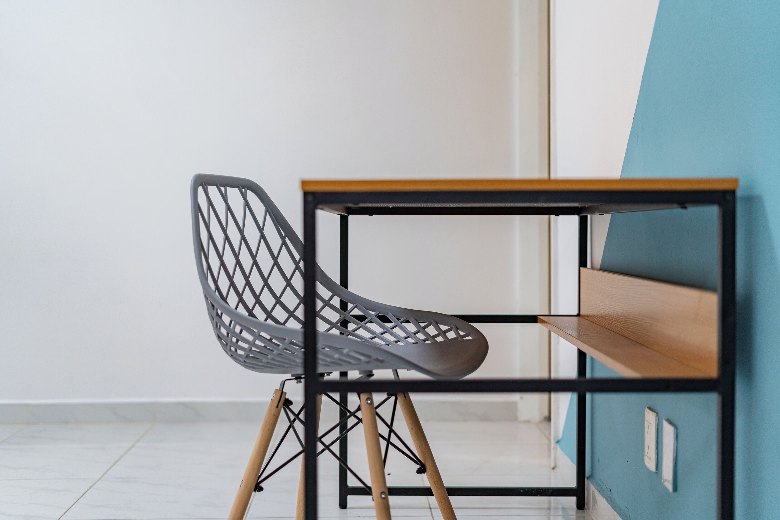 A chair with a metal frame and wooden legs, placed on a table with a black metal frame and wooden shelves.