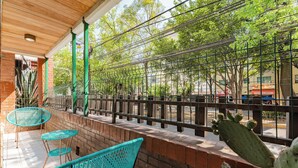 Een terras met turquoise stoelen en een cactussplant.