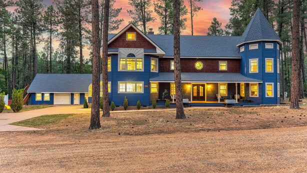 A large, two-story house with a wrap-around porch and a turret, surrounded by tall pine trees. - Strawberry Pines Retreat (Strawberry)