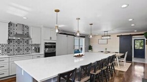 A modern kitchen with a large island, pendant lighting, and a view to the dining area. - Strawberry Pines Retreat (Strawberry)