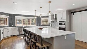 A modern kitchen with a large island, white cabinetry, and a black and white backsplash. - Strawberry Pines Retreat (Strawberry)
