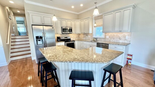 A modern kitchen with granite countertops, stainless steel appliances, and white cabinetry.