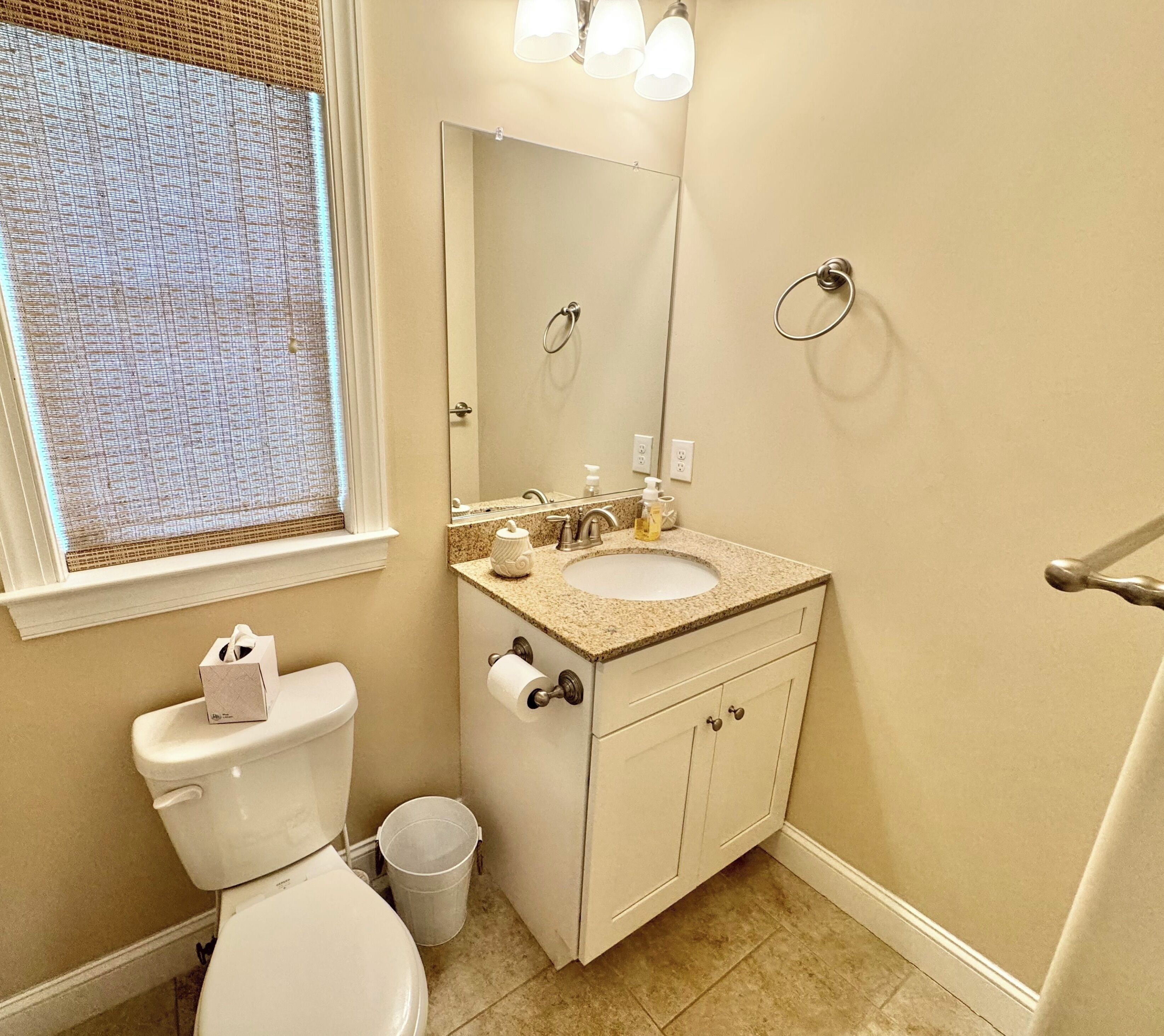Un baño con inodoro, lavabo, espejo y perchero para toallas.