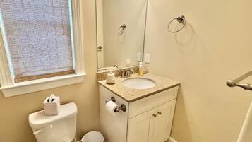 Un baño con inodoro, lavabo, espejo y perchero para toallas.