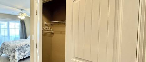A bedroom with a bed, a closet with a hanging rod, and a ceiling fan.