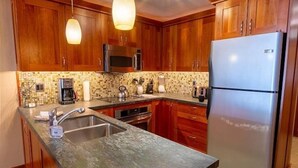 Una cocina con gabinetes de madera, un refrigerador de acero inoxidable, un microondas y una cafetera.