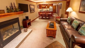 Una sala de estar con chimenea, un sofá de cuero, una mesa de centro y una zona de comedor con sillas y una mesa.