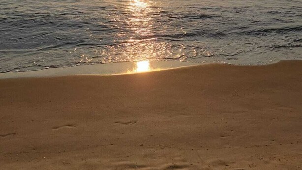 En strand där solen speglar sig i vattnet.