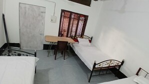 Ein Zimmer mit zwei Betten, einem Schreibtisch und einem Fenster mit Gitterstäben.