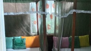 A room with two wooden beds, each with a canopy, and a green floor. - Hidden Jungle Village Wilpattu (Anuradhapura)