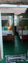 Una habitación con dos camas de madera, cada una con dosel, y piso verde.