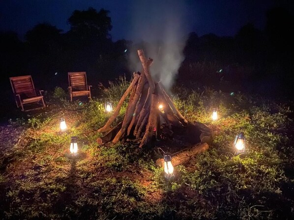 A campfire with lanterns around it, surrounded by chairs.