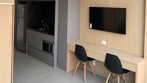 Un espace de vie compact comprenant un lit superposé, une kitchenette et un téléviseur fixé au mur.