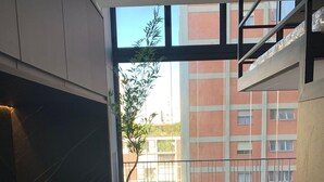 Une cuisine moderne dotée d’une grande fenêtre, d’un coin repas avec des chaises et d’une vue sur un bâtiment rouge.