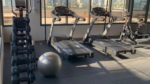 Une salle de sport équipée de tapis de course, d’haltères et de ballons d’exercice.