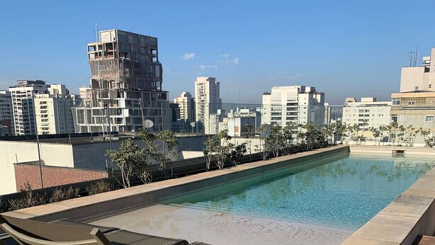 Une piscine sur le toit, dotée de chaises longues et offrant une vue sur la ville.