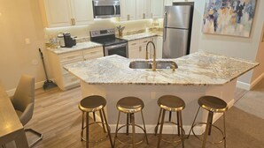 A modern kitchen with white cabinetry, stainless steel appliances, and a granite countertop.