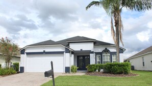 A modern two-story house with a garage, a well-maintained lawn, and a palm tree.
